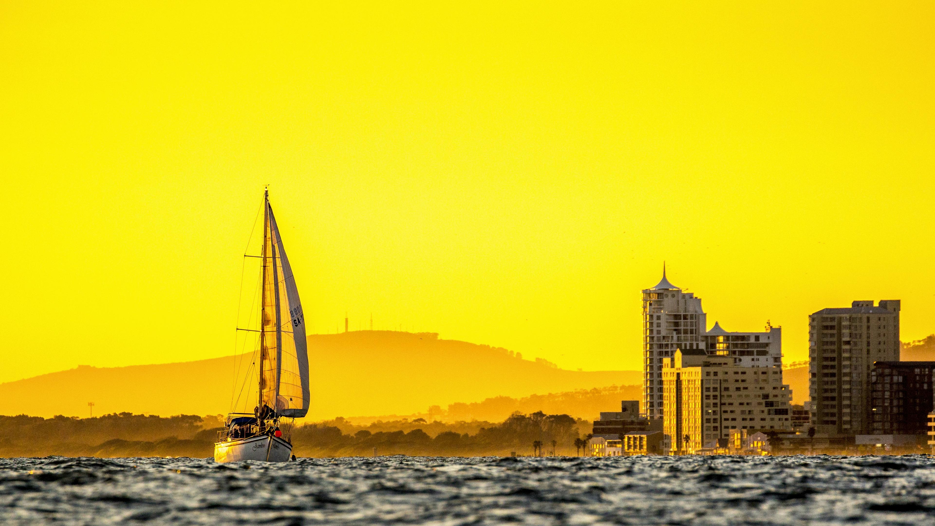 Duffy electric boat gliding through Newport Harbor at golden hour with waterfront estates in background