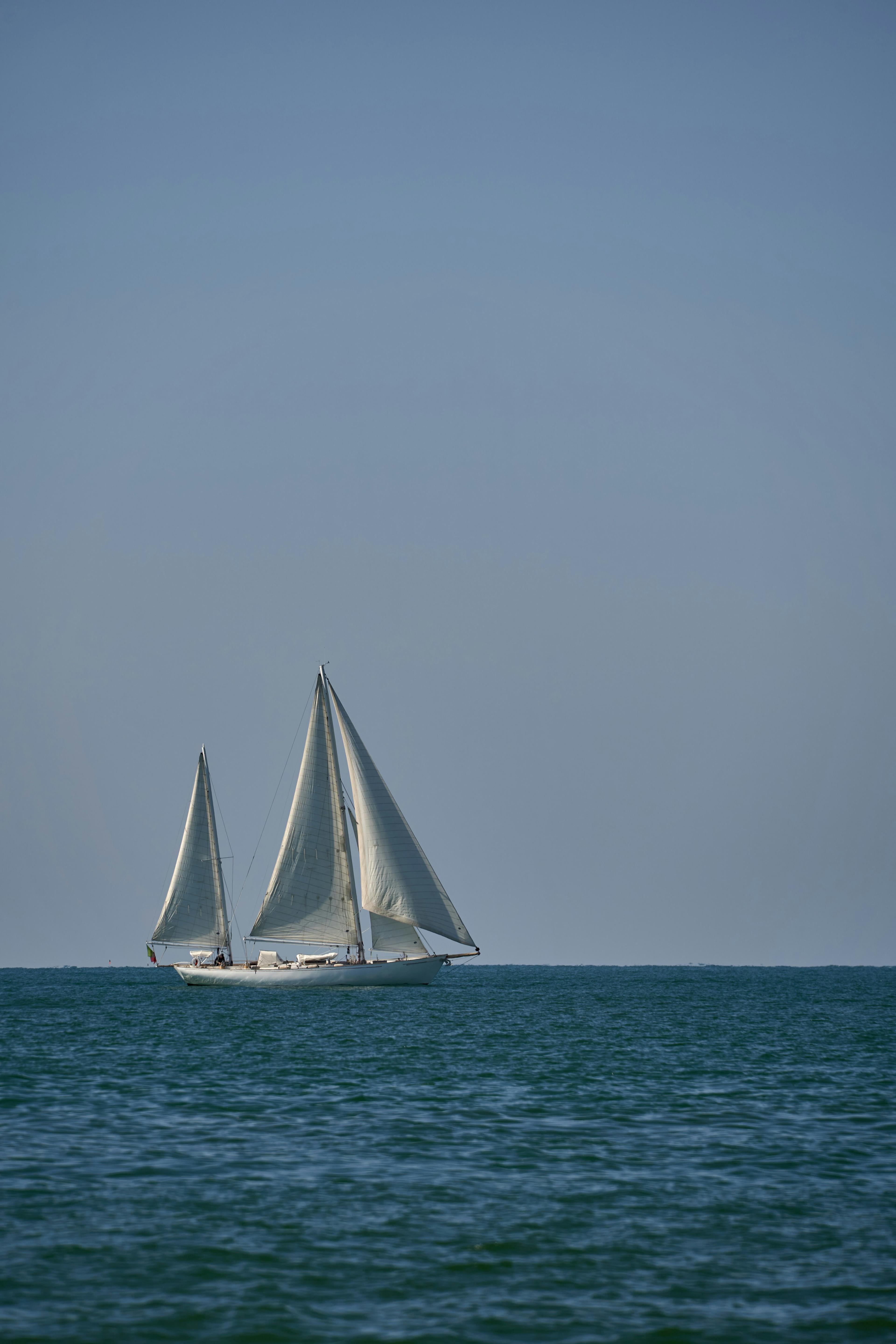 Sailboat under full sail heading toward Catalina Island from Newport Beach on a sunny day