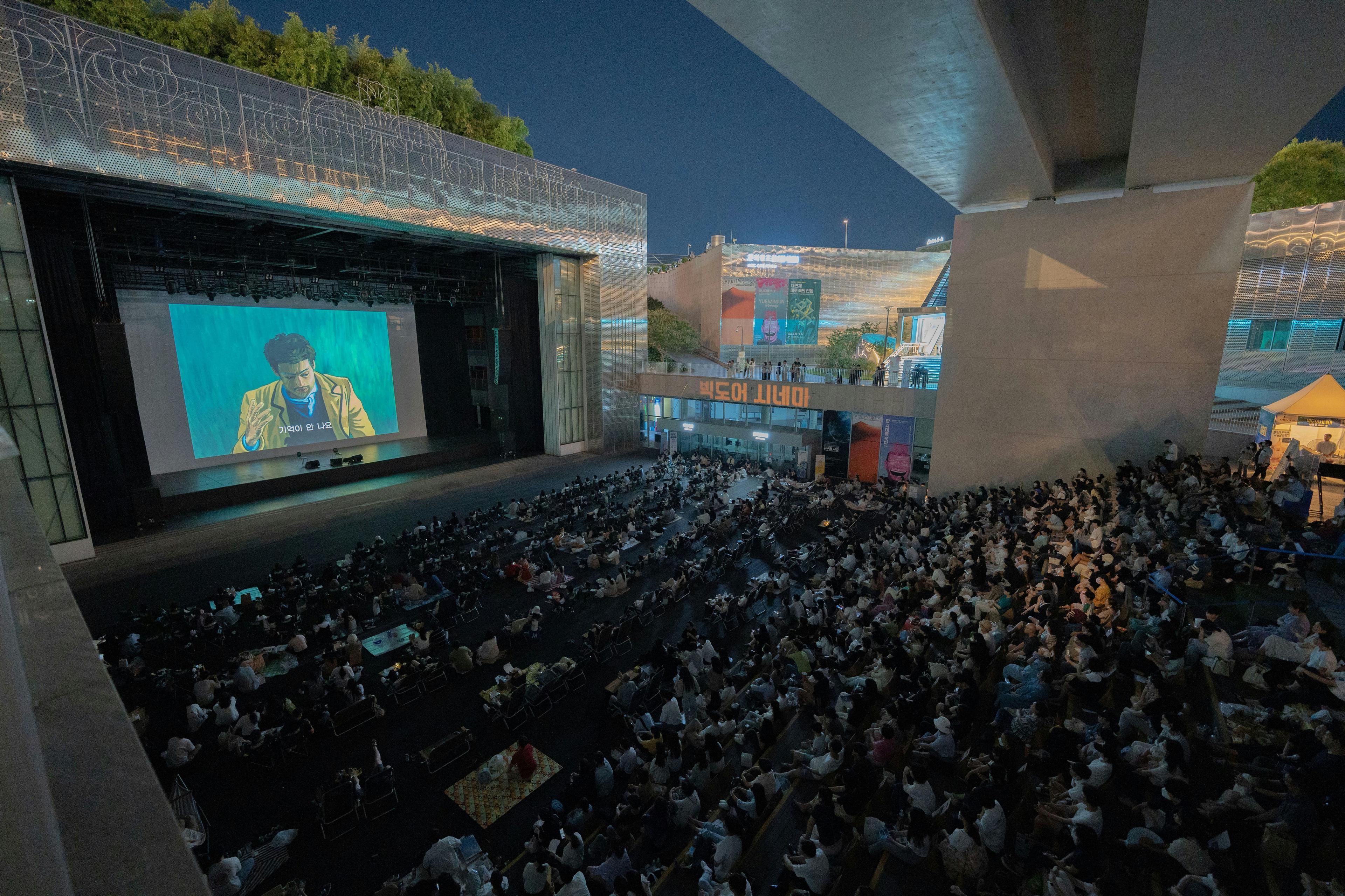 Film festival outdoor cinema screening with audience under the stars at night
