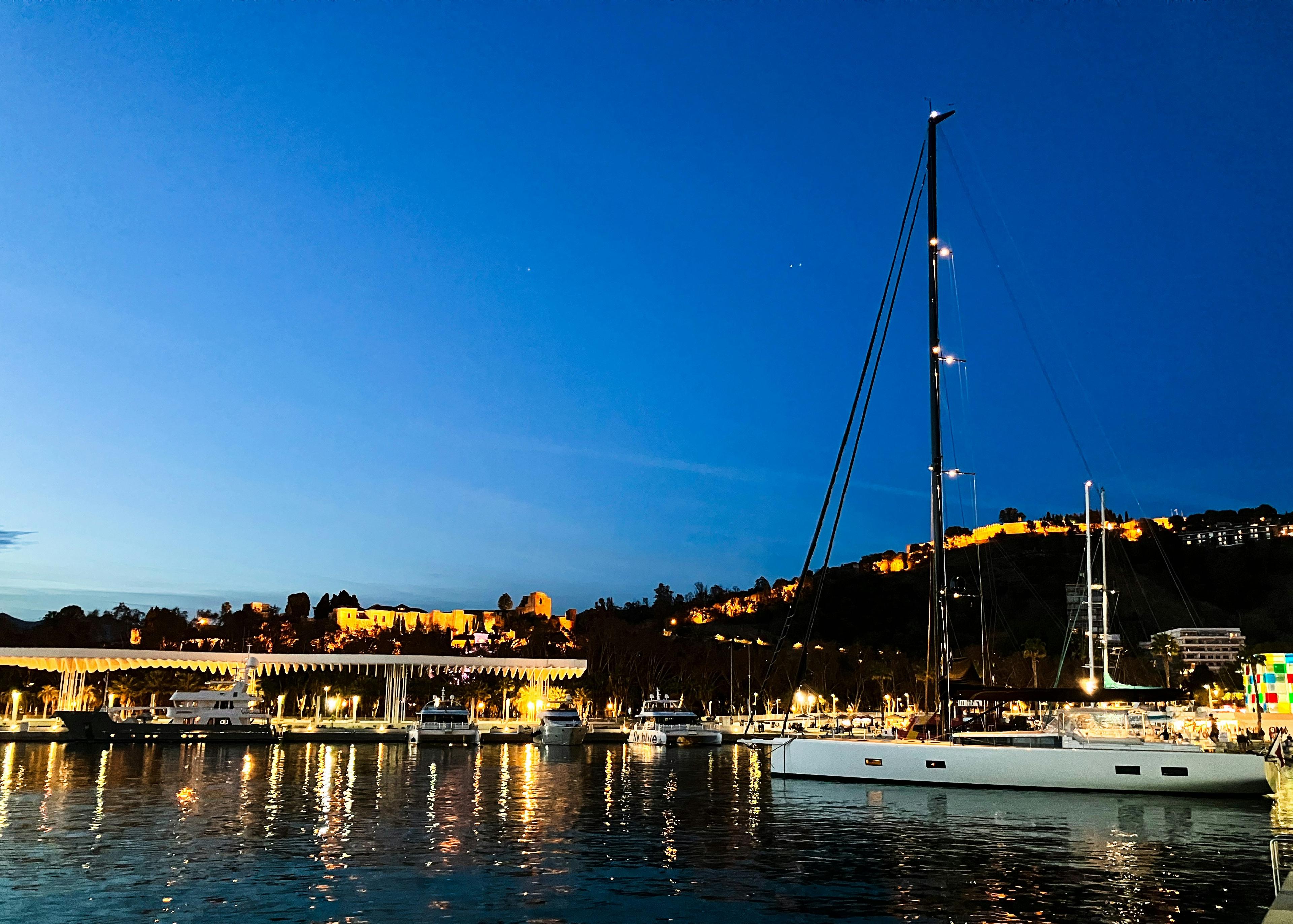 Professional private yacht captain at the helm of a sailboat navigating Newport Harbor at sunset