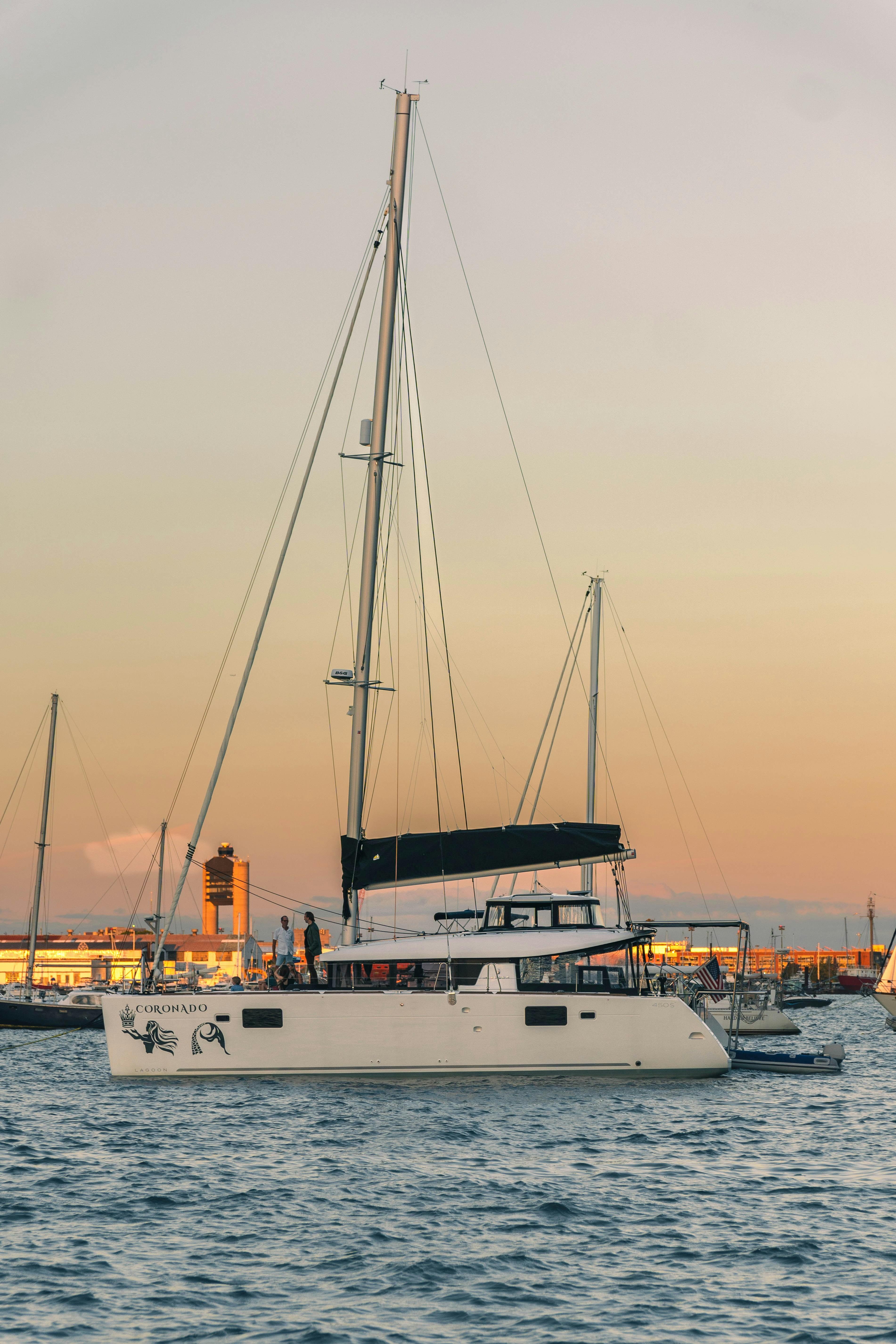 Private luxury yacht anchored in Newport Harbor at golden hour with crew on deck